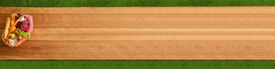 Top view of picnic basket with wine and grapes on wooden surface outdoor, space for text. Banner design