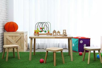 Stylish playroom interior with toys and modern wooden furniture