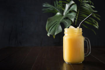 Fresh summer fruits smoothies with banana, lime on dark tropical wooden table. Space for text. Close up.