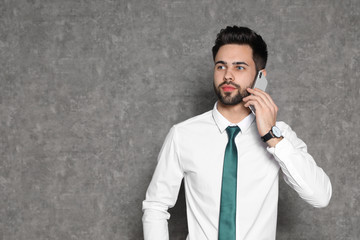 Portrait of businessman talking on phone against grey background. Space for text