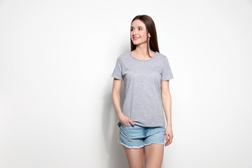 Young woman in t-shirt on light background. Mock up for design