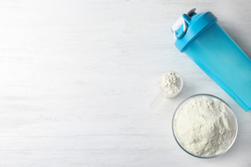 Flat lay composition with protein powder on white wooden table, space for text