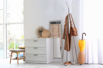 Modern hallway interior with chest of drawers and clothes on hanger stand