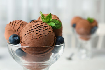 Glass bowl of chocolate ice cream on blurred background, closeup with space for text