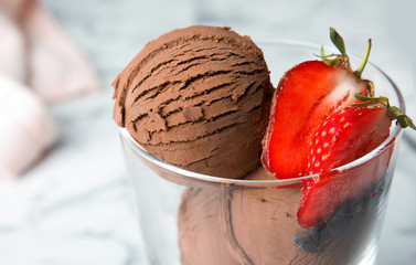 Glass of chocolate ice cream with strawberry on blurred background, closeup. Space for text
