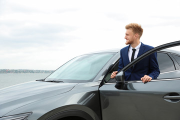 Young successful man near modern car outdoors