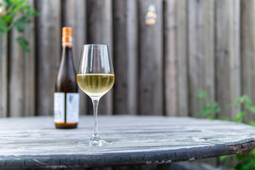 Image of white wine glass with white wine bottle and blurry background