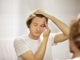 young man looking in the mirror,combing his hair,looking at problems on face