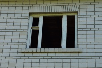  old empty window with wooden frame on a gray brick wall of an abandoned house