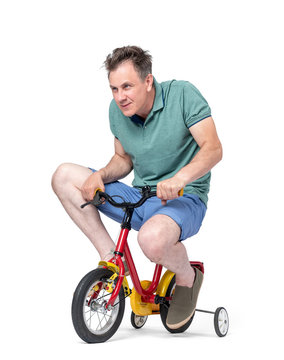Funny man in shorts and a t-shirt rides a children's bicycle, isolated on white background.