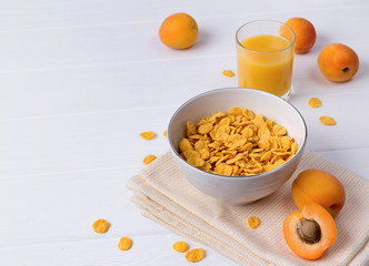 Corn Flakes with apricot at the white wooden table.
