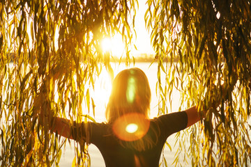 Autumn portrait of young girl with willow branches on the background of a lake at sunset © Sergiy