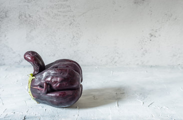 Trendy ugly organic eggplant on grey wooden table, with copy space
