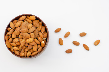 Brown wooden bowl full of almond on white background shot from abowe
