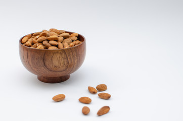 Almonds in brown wooden bowl on a white background
