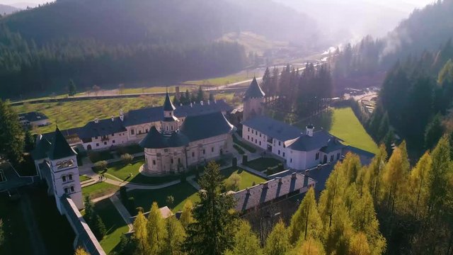 Aerial view of Putna medieval orthodox monastery. One of the most important Romanian monastery, (Unesco Heritage). Top view flying over monastery details in spring season. Green meadow landscape scene