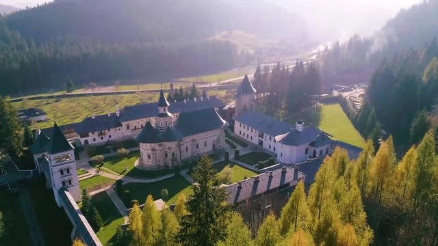 Aerial view of Putna medieval orthodox monastery. One of the most important Romanian monastery, (Unesco Heritage). Top view flying over monastery details in spring season. Green meadow landscape scene