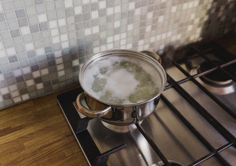 Saucepan on the stove in the kitchen on the background of a wooden tabletop