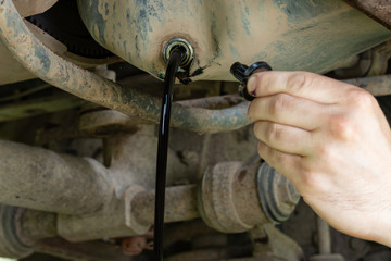 A jet of oil is poured from the crankcase. Auto mechanic holding the lid from the hole in the...