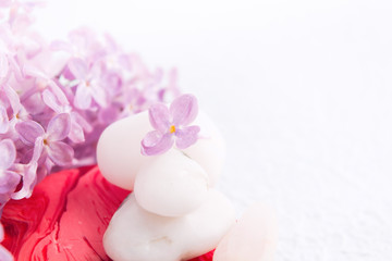Spa and massage relaxation concept with white stones. red handmade soap and lilac flowers with copy space
