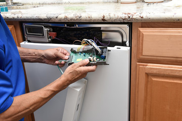 Closeup of a appliance repairman unplugging the control panel to a broken dishwasher