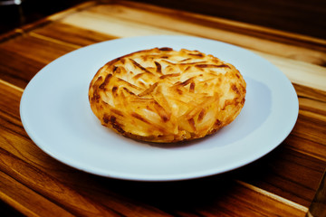 Cheesy potato rosti cake on white plate at restaurant