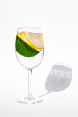 Wet glass with water and lemon. Lemon tree leaf. Hot weather drink. Healthy organic food background. Bright minimalistic clean photo. Sun light illumination. Vitamin C body nutrition element. 