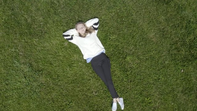 Girl relaxing in grass overhead view 4k