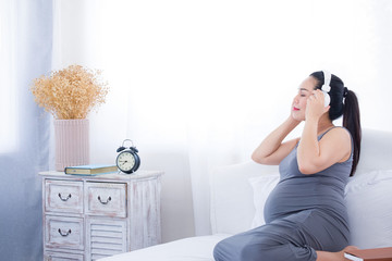 Pregnant woman listening to music on the bed. Mental health care and pregnancy.