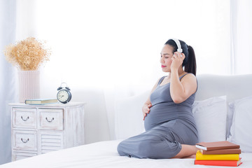 Pregnant woman listening to music and put her hand on belly. Mental health care and pregnancy.