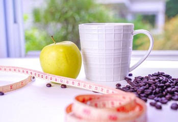 Fresh apple with coffee in a mug and measuring tape on a table. diet concept and healthy.
