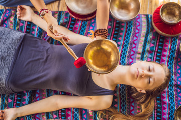 Nepal Buddha copper singing bowl at spa salon. Young beautiful woman doing massage therapy singing...