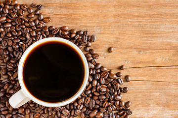 Fresh coffee with fragrant aroma in a white cup and coffee beans on an old wooden table. Top view - image