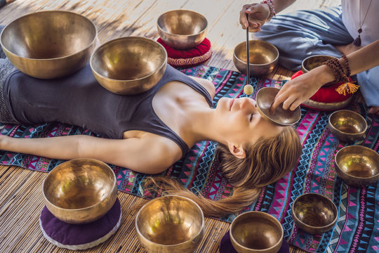 Nepal Buddha copper singing bowl at spa salon. Young beautiful woman doing massage therapy singing bowls in the Spa against a waterfall. Sound therapy, recreation, meditation, healthy lifestyle and