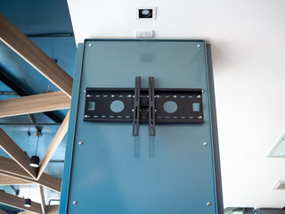 Black TV wall mount on blue steel pillar