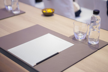 Paper, pencil, water bottle, glass on the table in the seminar room