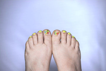 Close up of broken toe nail with cute painted. Even though the toenail is broken the women is being fun and positive. Two feet
