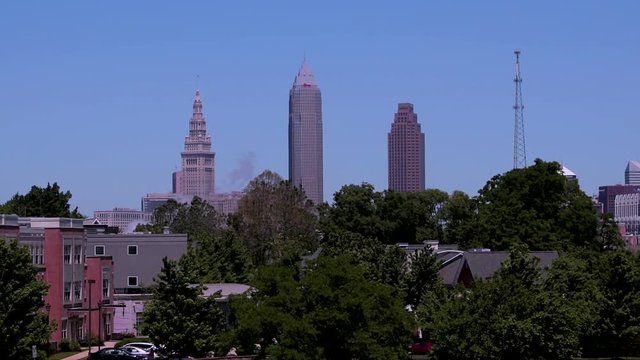 Cleveland, Ohio skyline as seen from the mounds in Tremont, a nearby neighborhood. The CLE big three building shine bright on a sunny day with blue skies.