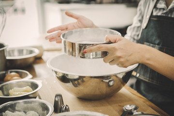 women are sifting flour to make bakery; happy family in kitchen