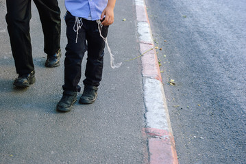 Religious Orthodox Jewish man and boy in traditional clothes and shabby shoe walk on Jerusalem...