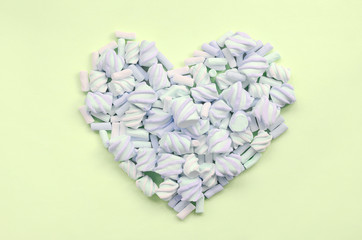 Colorful marshmallow laid out on lime and pink paper background. pastel creative textured heart