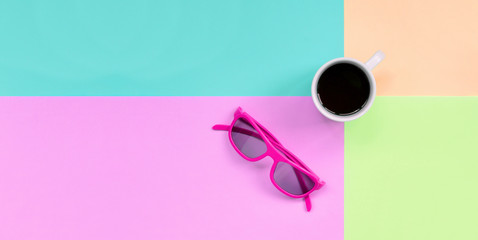 Small white coffee cup and pink sunglasses on background of fashion pastel pink, blue, coral and...