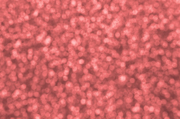 Blurred coral red decorative sequins. Background image with shiny bokeh lights from small elements