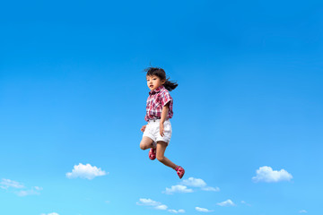 Fototapeta na wymiar 青空を背景にジャンプする幼児。希望、幸せ、飛躍、未来イメージ