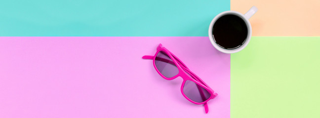 Small white coffee cup and pink sunglasses on background of fashion pastel pink, blue, coral and lime colors