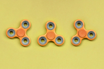 Many orange fidget spinners lies on texture background of fashion pastel orange color paper