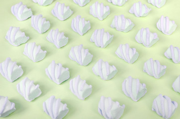 Colorful marshmallow laid out on lime paper background. pastel creative textured pattern