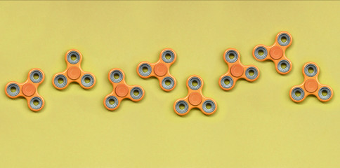 Many orange fidget spinners lies on texture background of fashion pastel orange color paper