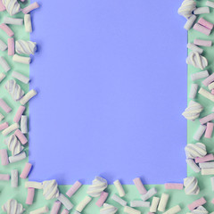 Colorful marshmallow laid out on green and lilac paper background