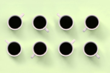 Many small white coffee cups on texture background of fashion pastel lime color paper